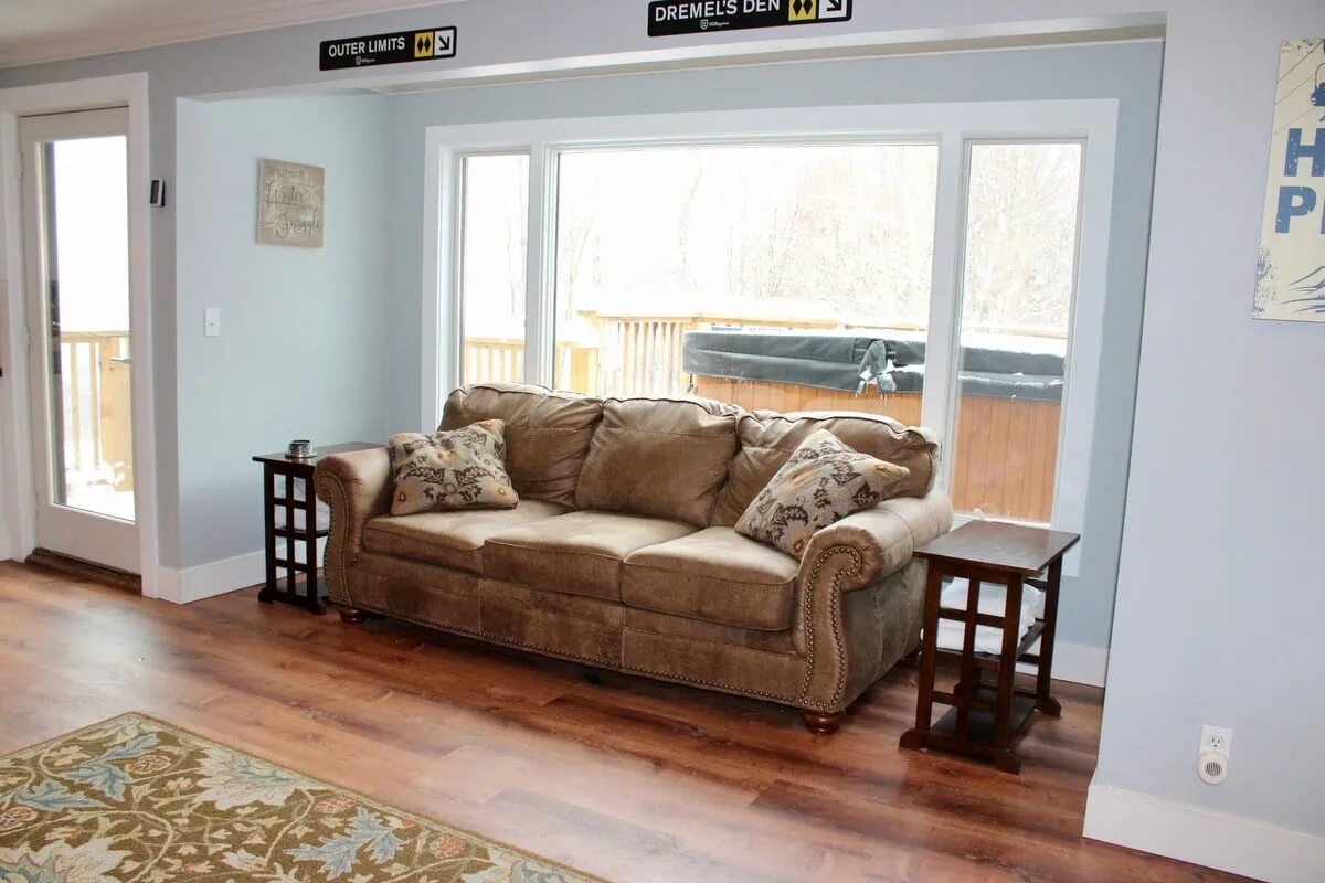 A cozy seating area with a soft sofa, decorative pillows, and expansive windows framing the outdoors. The mood is tranquil, allowing for relaxation, reading, or simply watching the snowfall outside.
