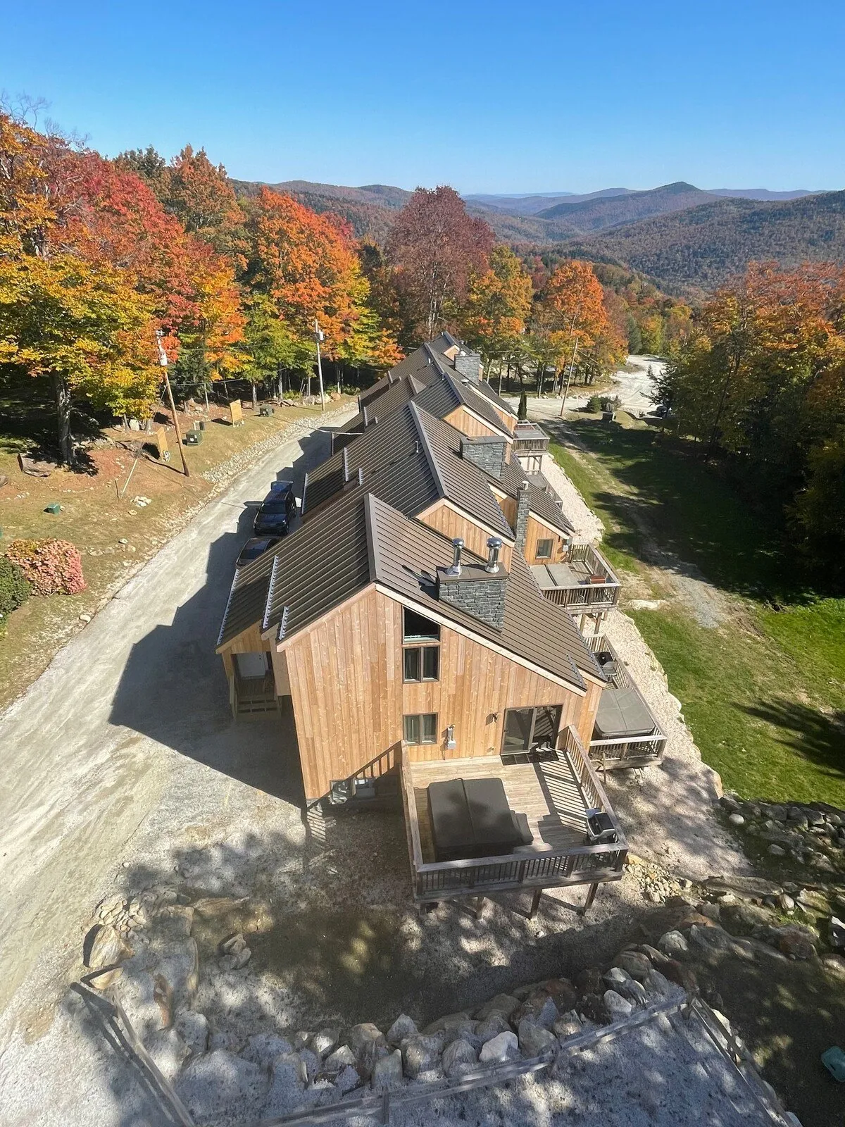 A tranquil mountain scene showcasing wooden cabins enveloped by stunning autumn foliage with expansive mountain views. The area encourages exploration and offers a peaceful backdrop for outdoor activities with pets.