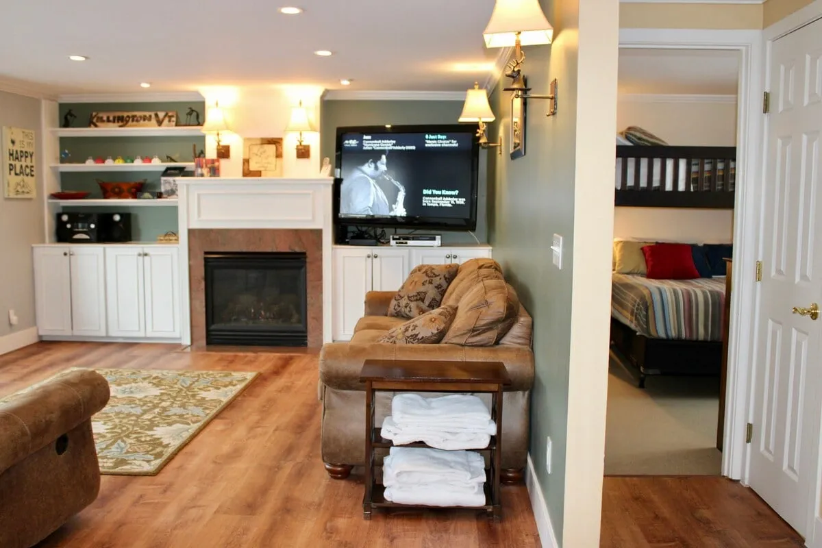 A living room setup with a modern fireplace, a plush sofa, a wall-mounted television, and decorative shelving, creating a comfortable and homely atmosphere ideal for family gatherings or movie nights.
