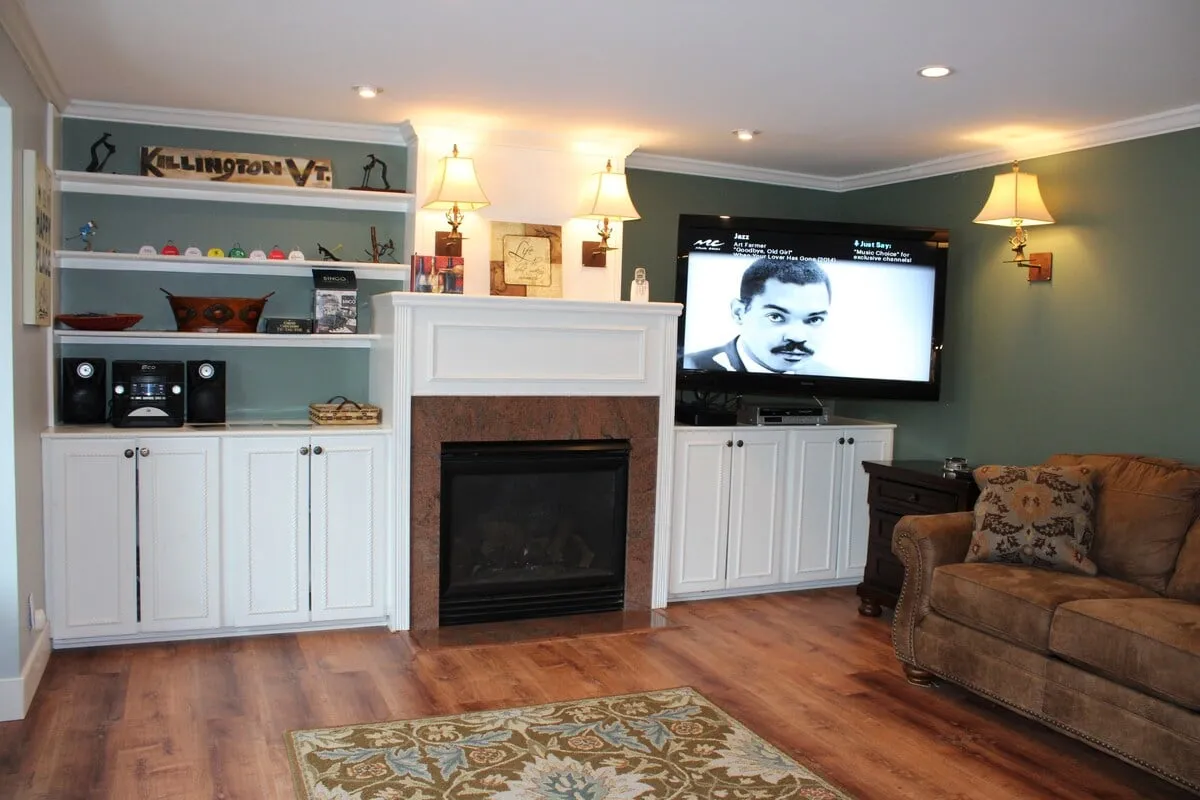 A warm, inviting living room centered around a crackling fireplace. The space features a plush sofa, a television, and decorative shelves, all arranged to encourage cozy evenings by the fire or intimate movie nights.